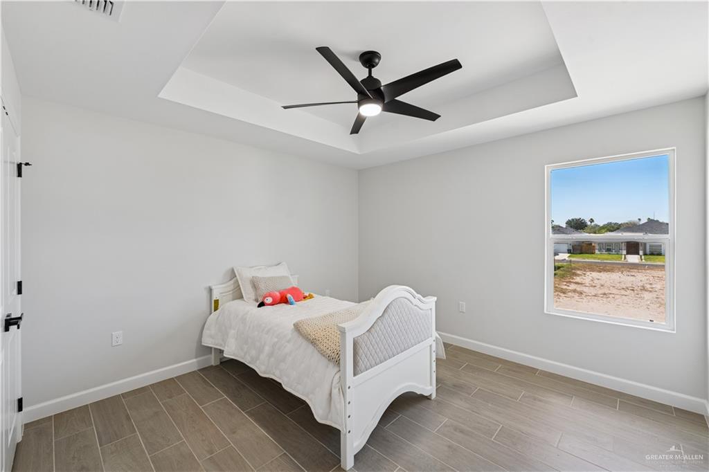1013 Azalea Street Mission, TX 78573 - Photo 28 of 35 Bedroom featuring a tray ceiling, wood finish floors, and a ceiling fan