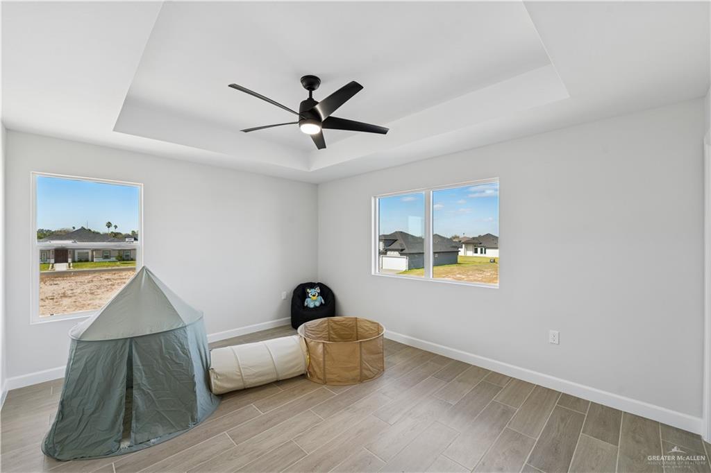 1013 Azalea Street Mission, TX 78573 - Photo 30 of 35 Living area with a tray ceiling, wood finish floors, and a ceiling fan