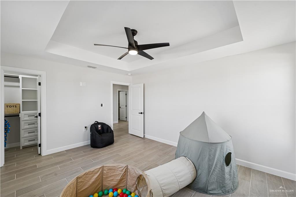 1013 Azalea Street Mission, TX 78573 - Photo 31 of 35 Playroom featuring wood tiled floors, a tray ceiling, and ceiling fan