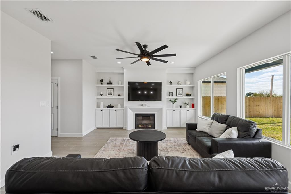 1013 Azalea Street Mission, TX 78573 - Photo 8 of 35 Living room with a glass covered fireplace, light wood-type flooring, ceiling fan, built in shelves, and recessed lighting