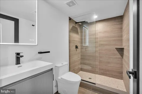 a bathroom with a sink a toilet a mirror and shower