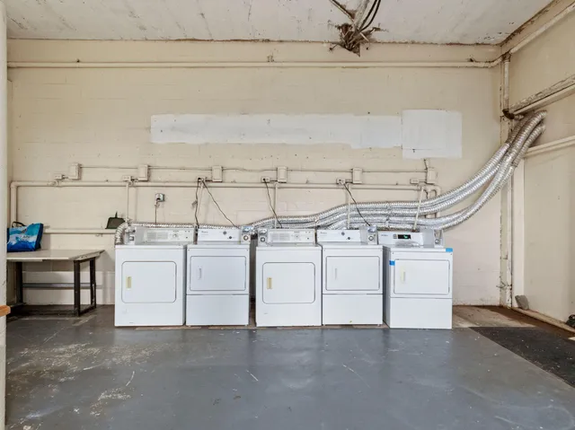 a utility room with dryer and white cabinets