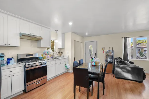 a kitchen with stainless steel appliances a stove a sink a dining table and chairs