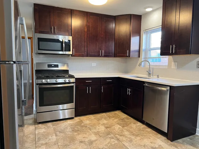 a kitchen with stainless steel appliances granite countertop a stove a sink and a microwave