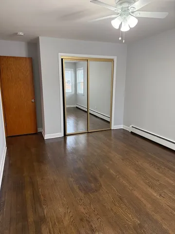 an empty room with wooden floor chandelier fan and windows