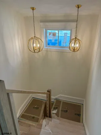 a view of a room with a hanging light and kitchen view