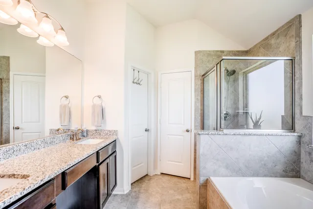 a bathroom with a granite countertop bathtub and shower