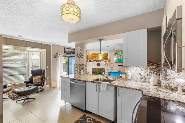 a view of a kitchen with kitchen island granite countertop a sink appliances and cabinets