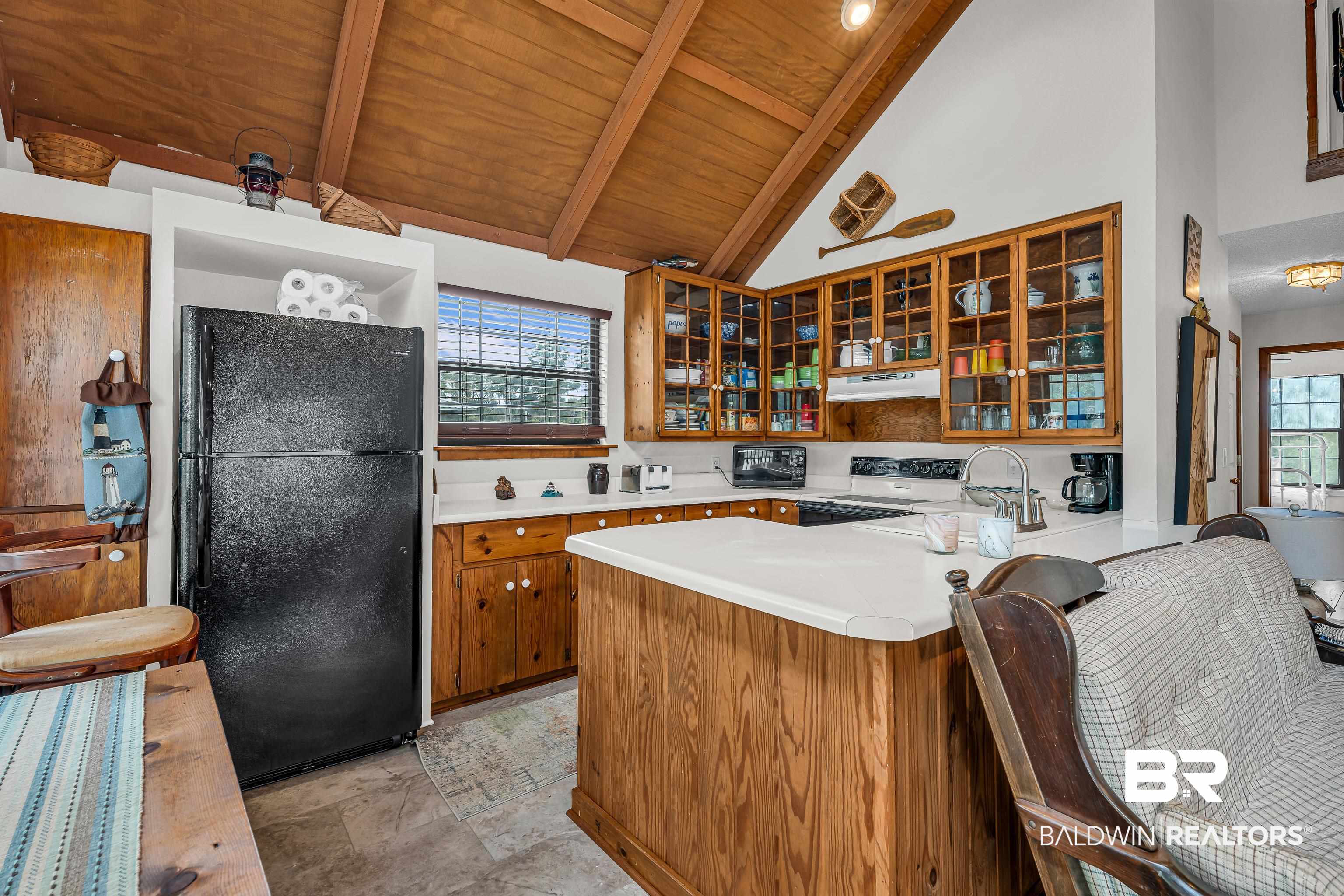 8317 Bryant's Lndg Road Stockton, AL 36579 - Photo 13 of 28 Kitchen with glass insert cabinets, freestanding refrigerator, light countertops, a peninsula, and a wooden ceiling with exposed beams