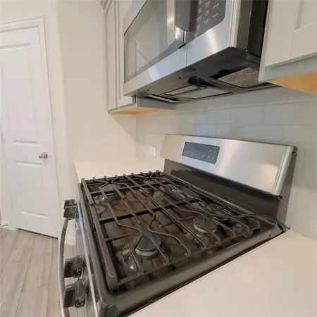 a stove sitting inside of a kitchen with white cabinets