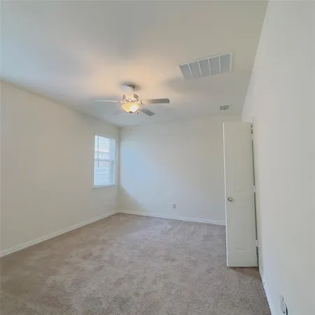 an empty room with windows and chandelier fan