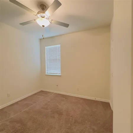 an empty room with a window and a fan