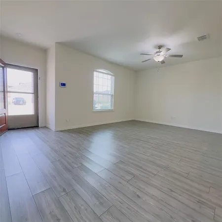 an empty room with wooden floor chandelier fan and windows