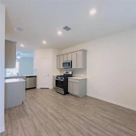 a large kitchen with a wooden floor and stainless steel appliances