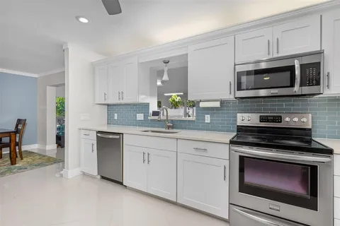 a kitchen with white cabinets stainless steel appliances and dining table