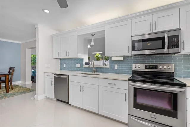 a kitchen with white cabinets stainless steel appliances and dining table