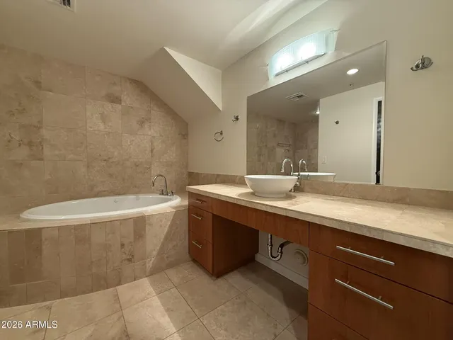a bathroom with a tub a sink and mirror