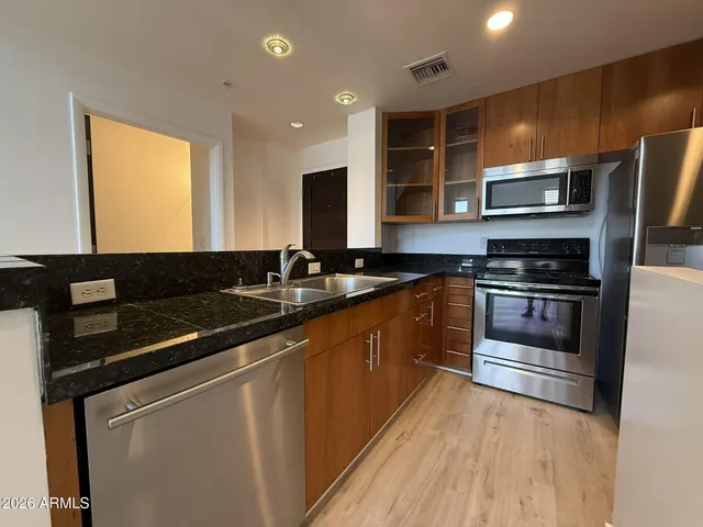 a kitchen with stainless steel appliances kitchen island granite countertop a stove and a refrigerator