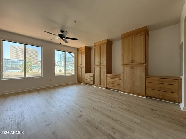 an empty room with wooden floor cabinet and windows