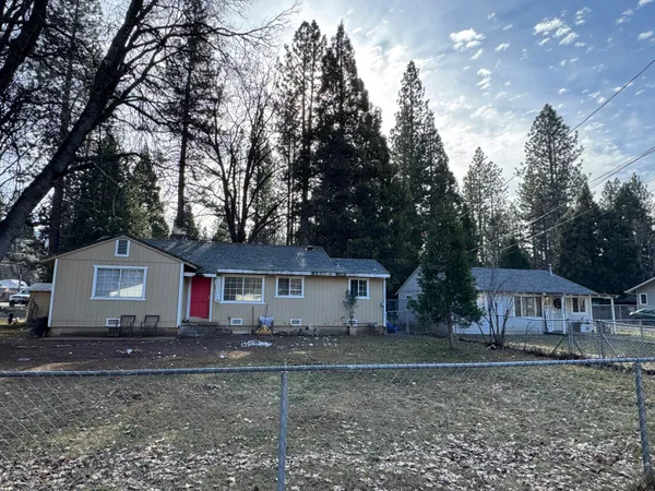 a front view of a house with yard and large tree