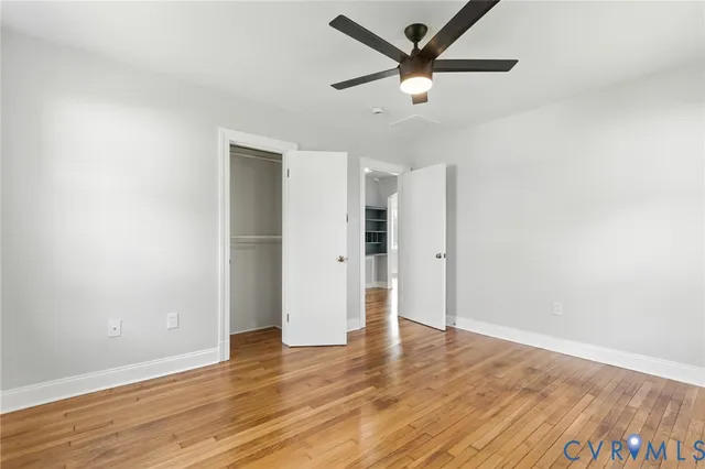 an empty room with wooden floor and a ceiling fan