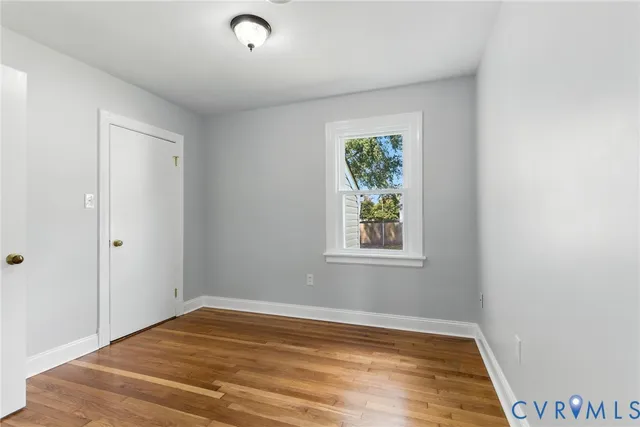 a view of empty room with window and wooden floor