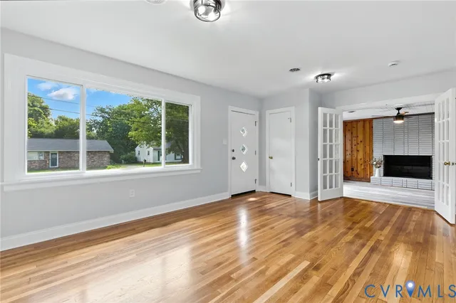 a view of an empty room with a window and wooden floor