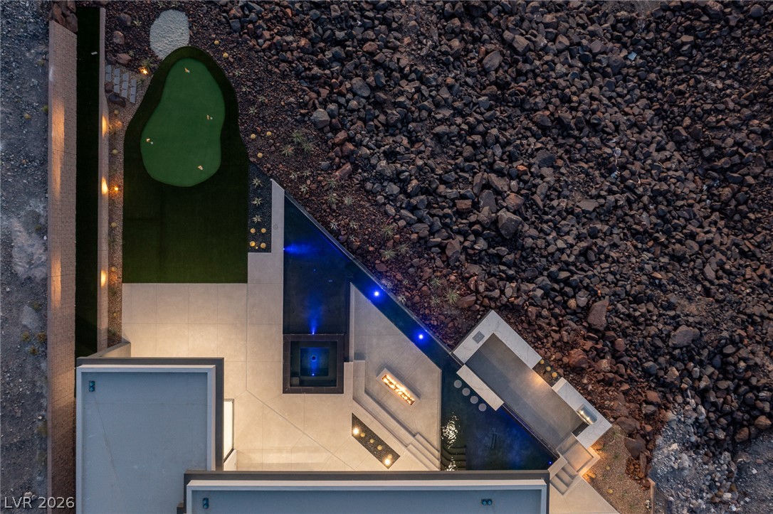 563 Grand Rim Drive Henderson, NV 89012 - Photo 57 of 70 An aerial perspective reveals a private putting green alongside a serene pool and patio, perfectly integrated with the natural, rocky landscape.