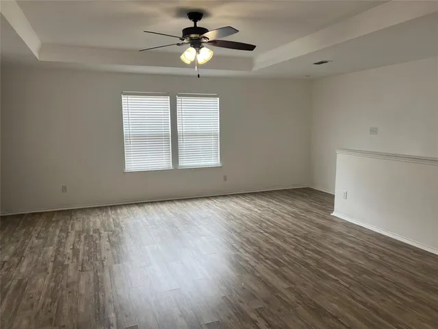 a view of an empty room with a window and wooden floor