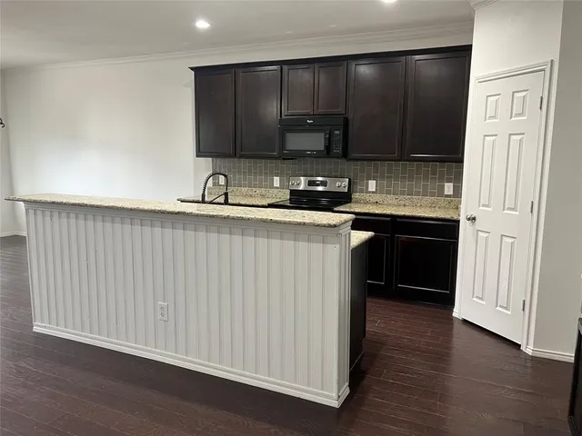 a kitchen with stainless steel appliances granite countertop a sink and cabinets with wooden floor