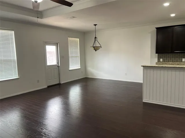 an empty room with wooden floor windows and ceiling fan
