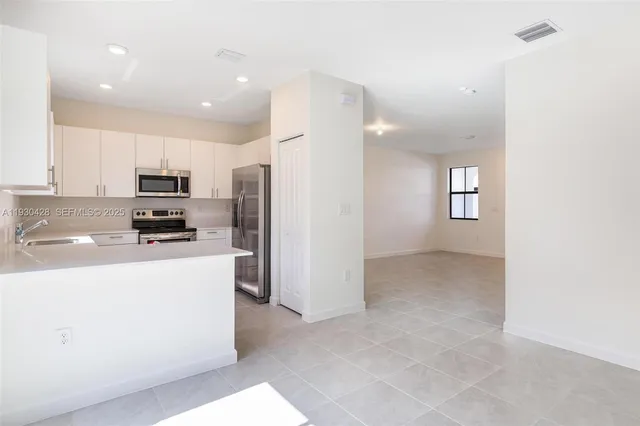 a kitchen with kitchen island granite countertop a refrigerator stove top oven and sink