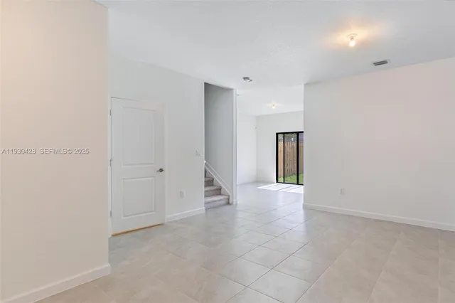 a view of an empty room with window and stairs
