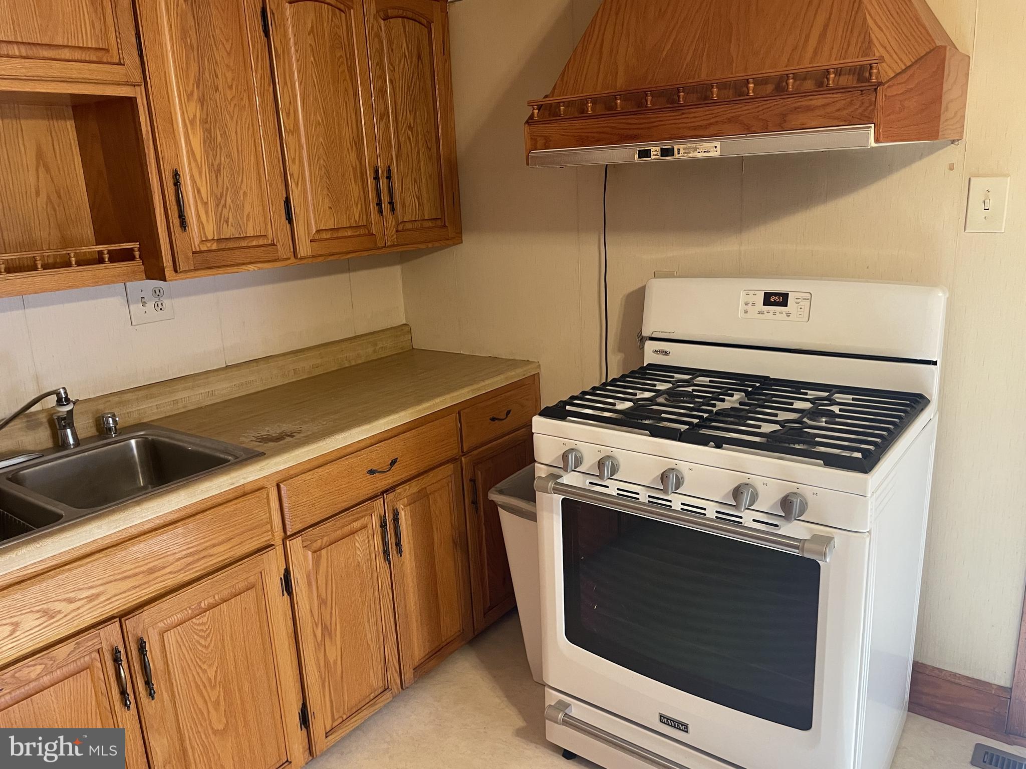 4420 West Denneys Road Dover, DE 19904 - Photo 17 of 36 a kitchen with granite countertop a stove sink and cabinets