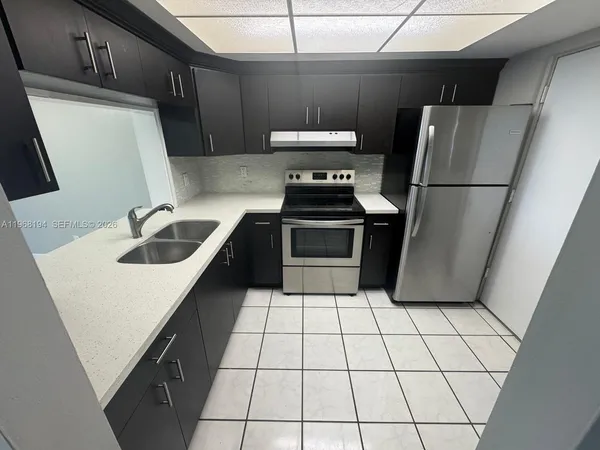 a kitchen with sink a refrigerator and a stove top oven