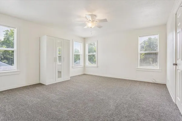 an empty room with windows and chandelier fan