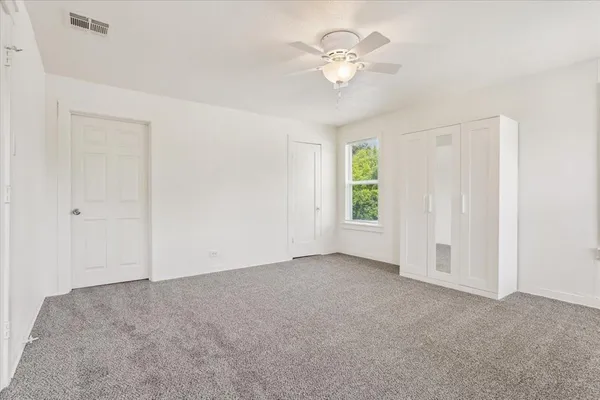 an empty room with windows and fan
