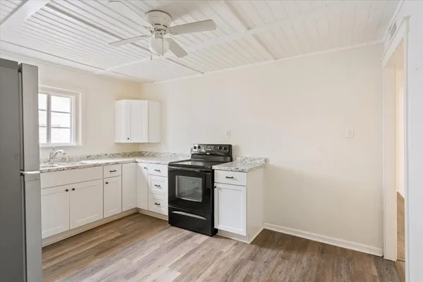 a kitchen with granite countertop a sink cabinets stainless steel appliances and a window