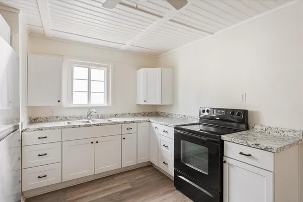a kitchen with granite countertop white cabinets and white appliances