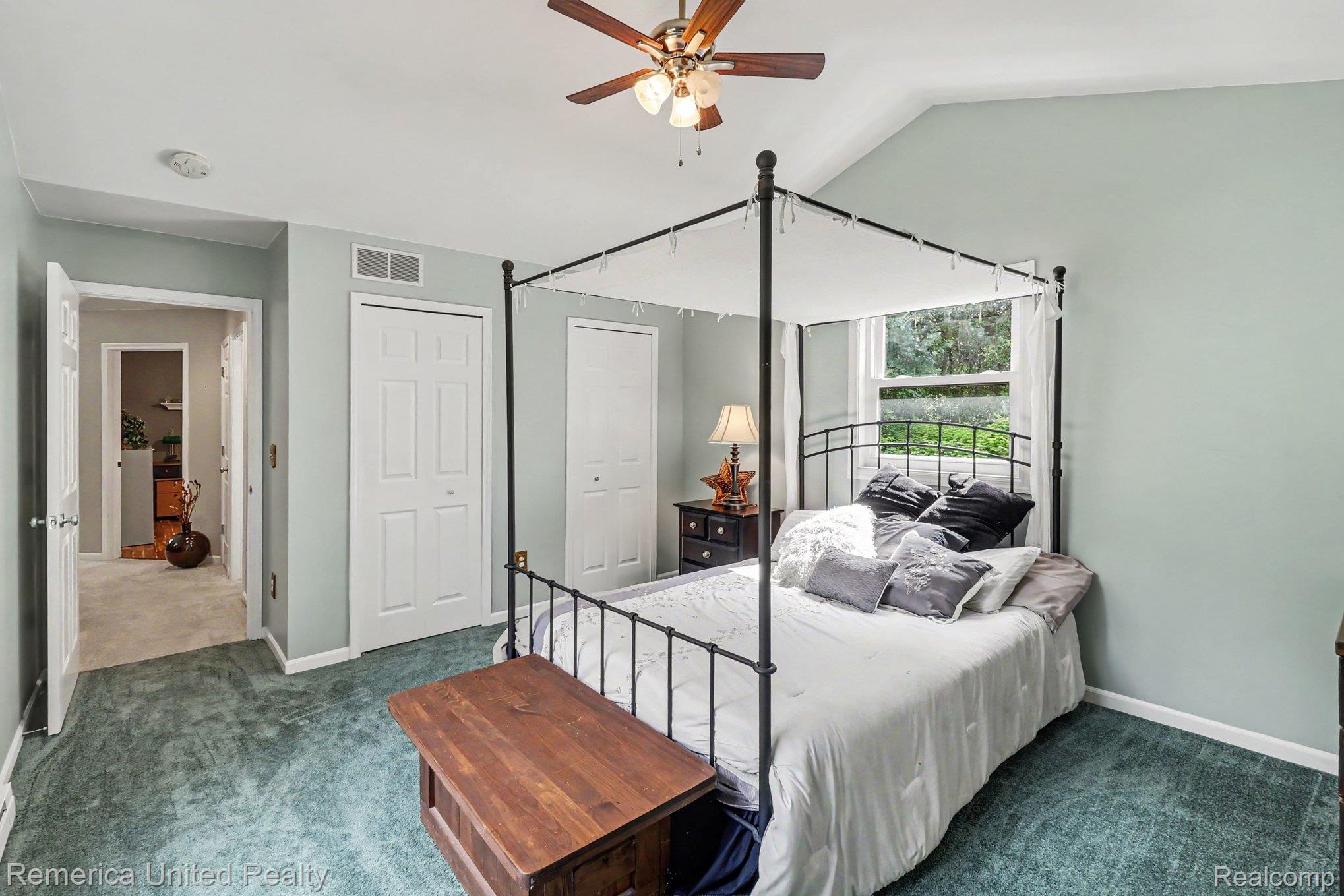 20962 Wasson Road Gregory, MI 48137 - Photo 21 of 39 Vaulted ceiling bedroom with a ceiling fan, plush green carpeting, bi-fold closet doors, and a window