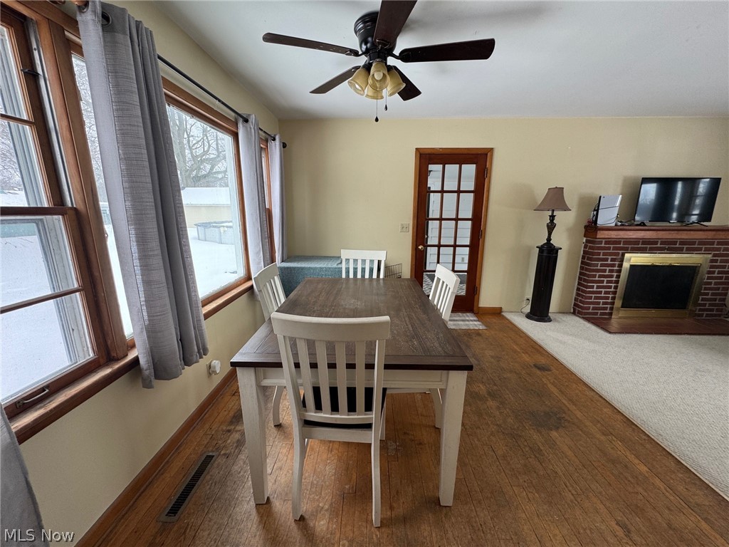 3828 Lake Road West Ashtabula, OH 44004 - Photo 18 of 29 Dining room featuring dark wood-style floors, a fireplace, and a ceiling fan