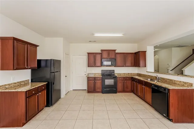 a kitchen with stainless steel appliances granite countertop a stove top oven a sink dishwasher and a refrigerator