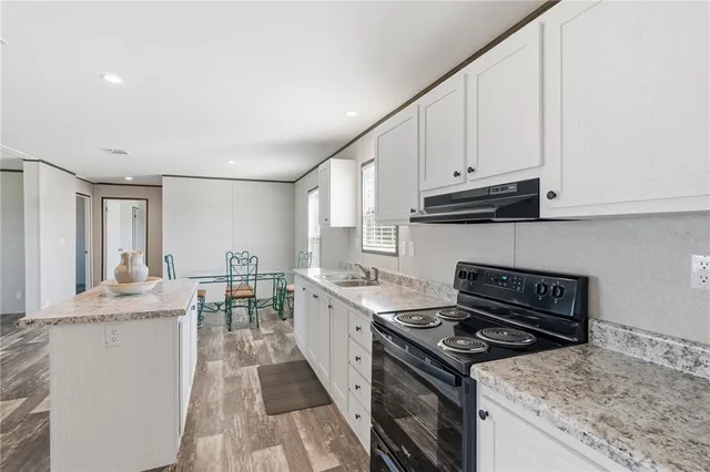 a kitchen with granite countertop a sink stove and cabinets