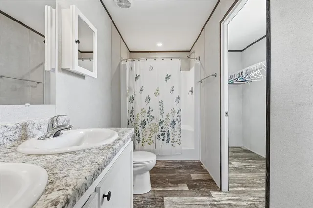 a bathroom with a granite countertop sink a toilet and shower