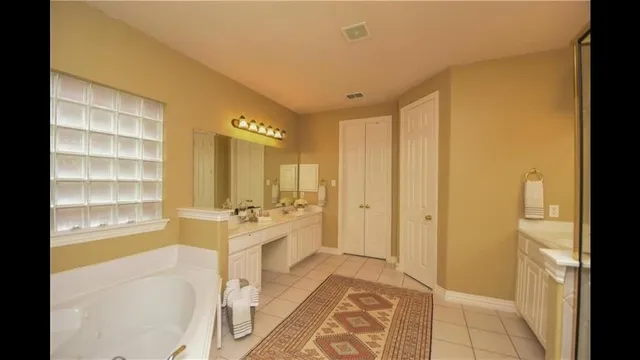 a spacious bathroom with a double vanity sink a mirror and a bathtub