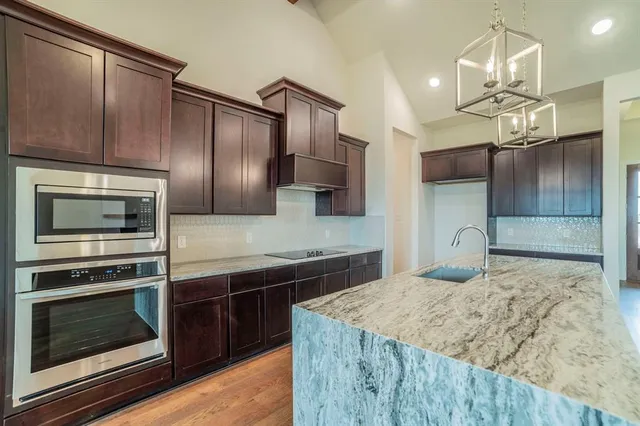 a kitchen with kitchen island granite countertop a sink cabinets and wooden floor
