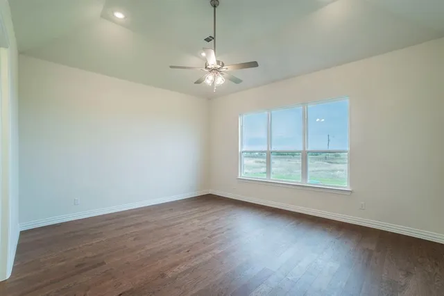 an empty room with wooden floor chandelier and windows