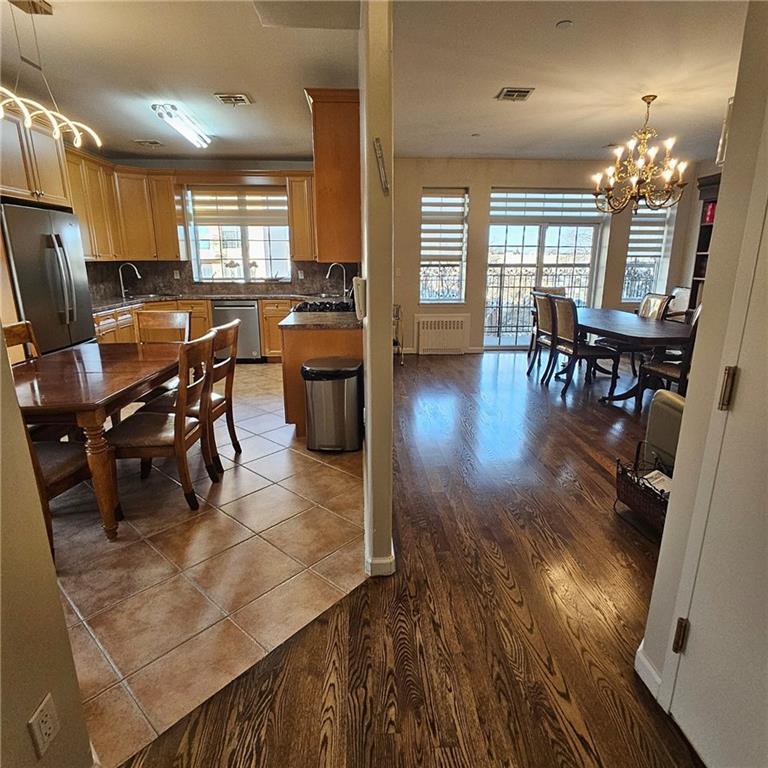 1012 41st Street, Unit 4 Brooklyn, NY 11219 - Photo 4 of 12 a kitchen with stainless steel appliances wooden floor dining table and chairs