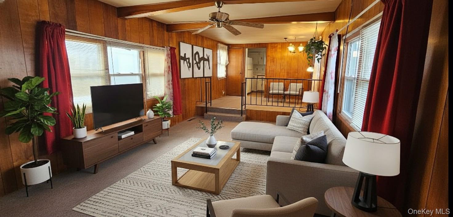 1964 River Road, Unit 35 Calverton, NY 11933 - Photo 4 of 16 Living room featuring carpet, wood walls, beamed ceiling, healthy amount of natural light, and ceiling fan
