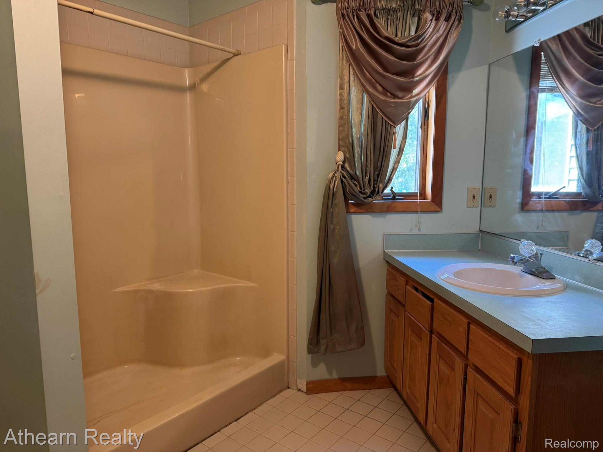 11449 Torrey Road Fenton, MI 48430 - Photo 20 of 30 Integrated shower stall with corner shelf, wood-finish vanity with built-in sink, framed window, and wall-mounted mirror